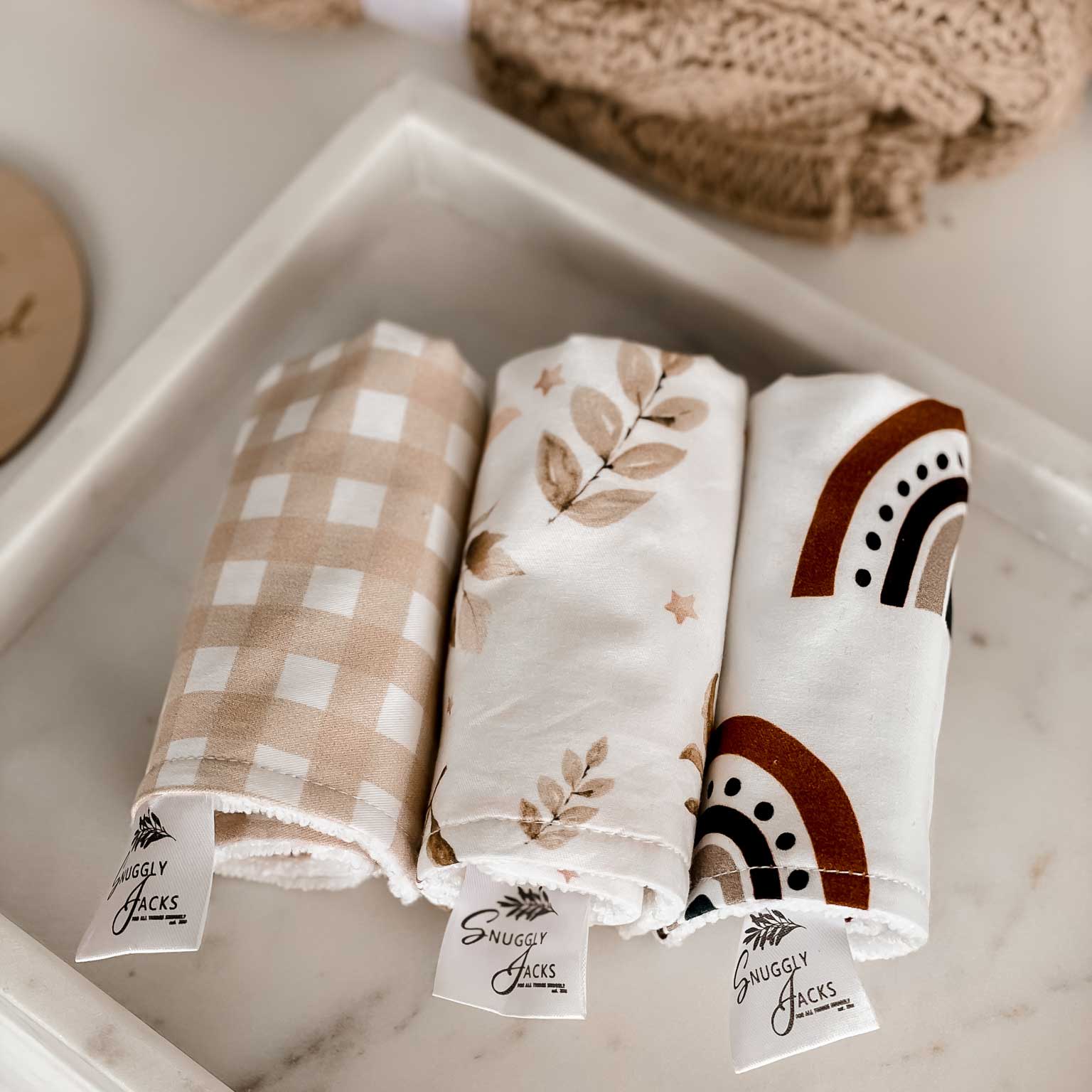 3 rolled wash cloths laying on a marble plate