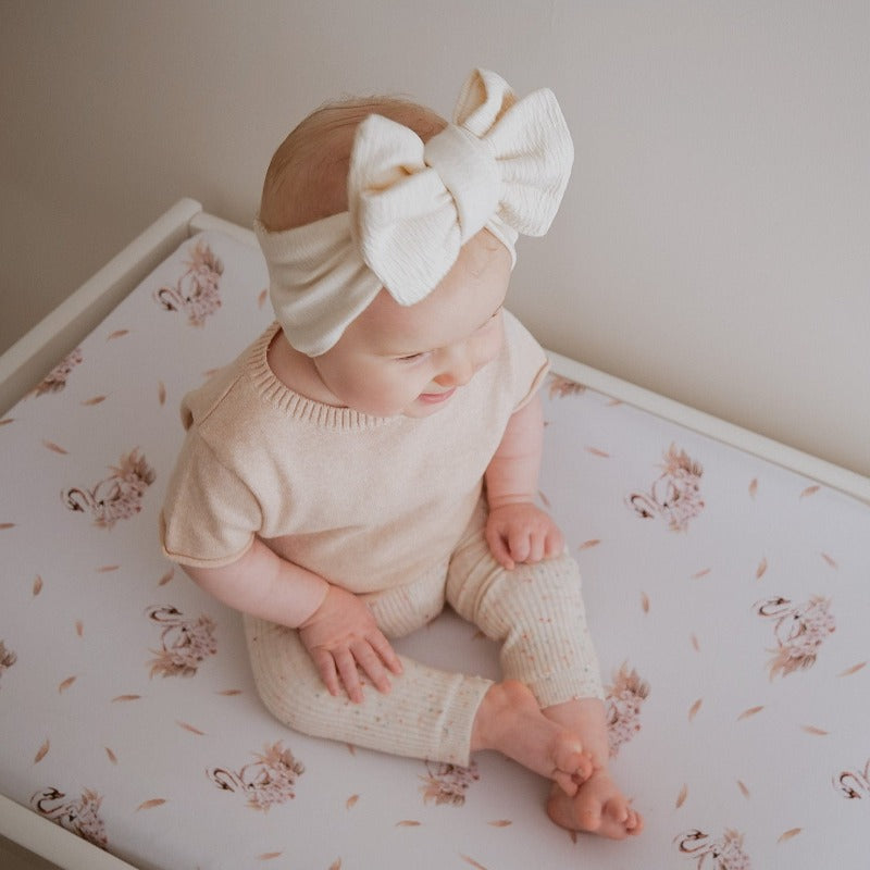 Sweet baby sitting on a change table wearing a cute linen bow.