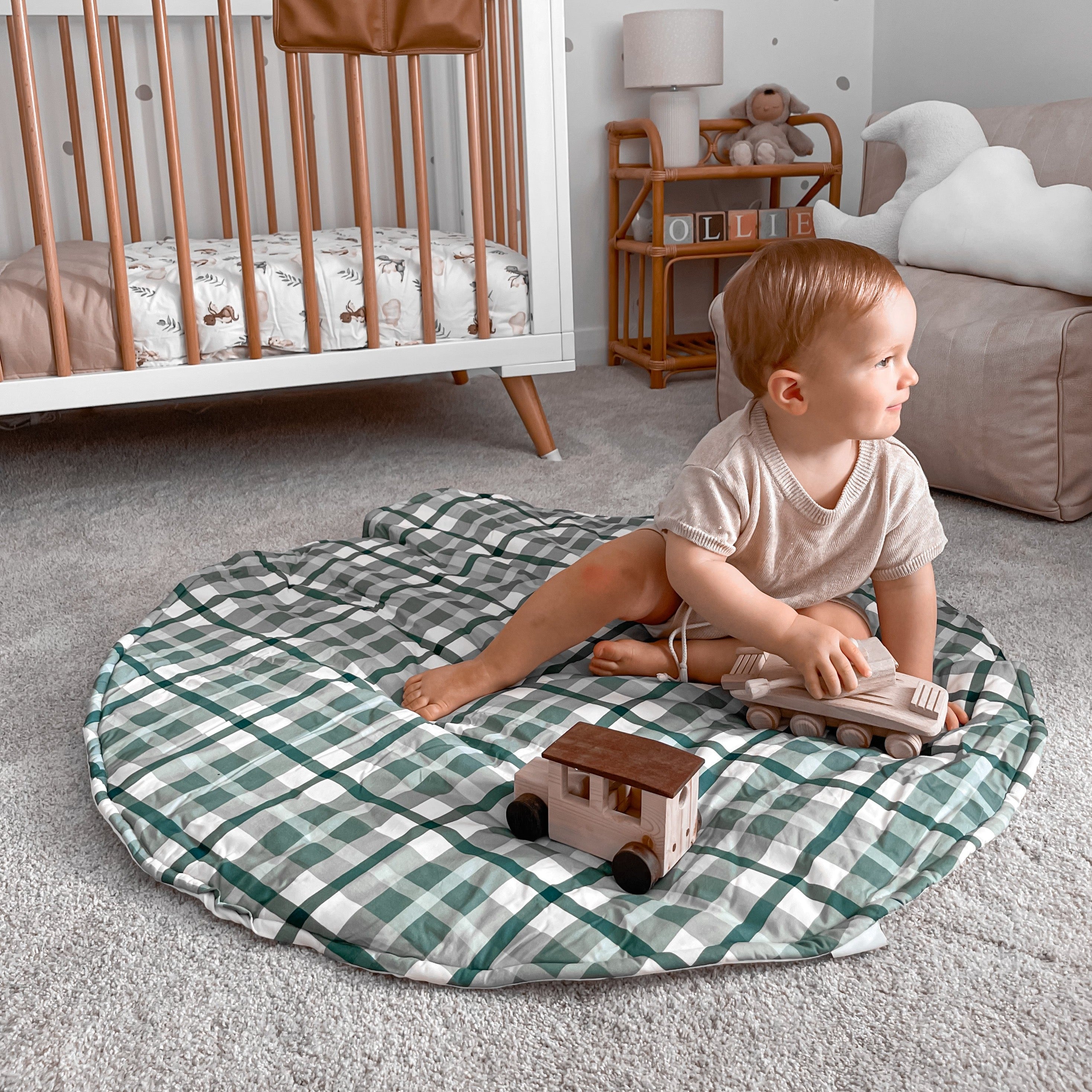 Toddler using his wooden toys on a blue plaid playmat in a modern nursery
