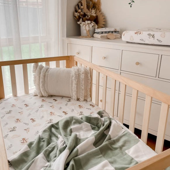 Modern nursery designed using dragon prints on a fitted crib sheet, bassinet cover and burp cloths.