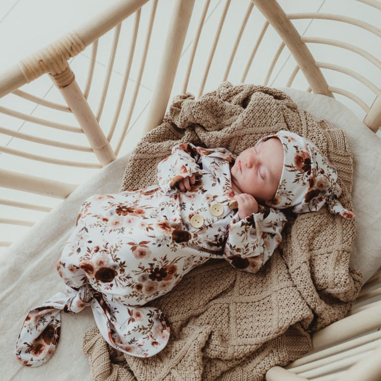 An overhead image of a cane bassinet with a sweet baby sleeping