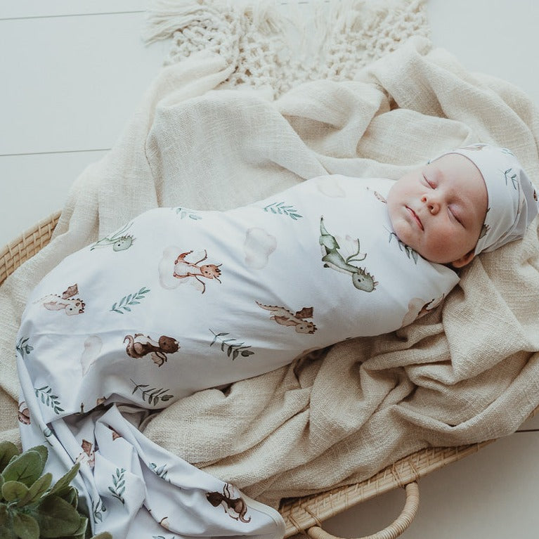 Tightly swaddled baby laying in a rattan moses basket, dreaming about all the sweet things