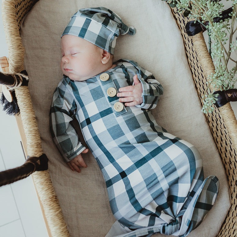 A cute baby sleeping in a bassinet wearing a beanie and a cotton onesie