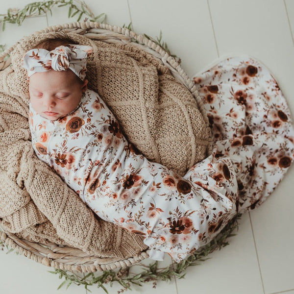 Sweet little baby snuggled in to a taupe knitted blanket and wrapped in a warm floral jersey stretch wrap 