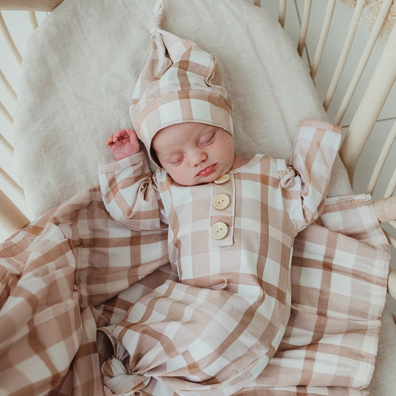 Sleeping baby in a bassinet wearing a knotted gown and matching beanie