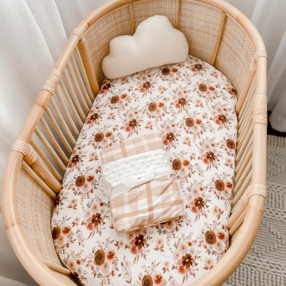 Rattan Bassinet set with a selection of snuggly jacks cotton products in warm browns and soft pinks.