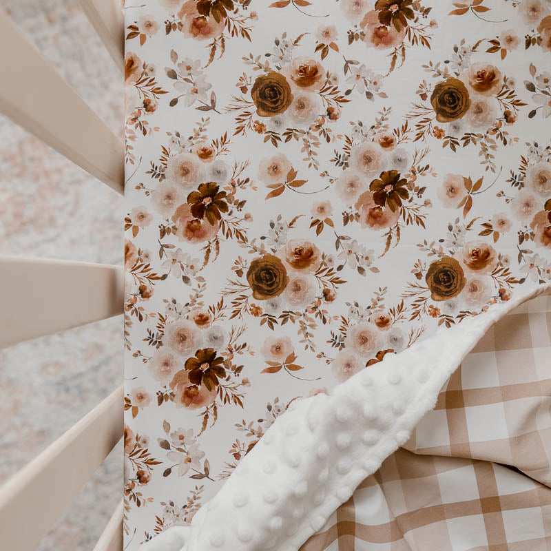 Snuggly Jacks Canada willow Floral fitted crib sheet shown in a pine crib with an earthy plaid dimple dot minky blanket draped over one corner.