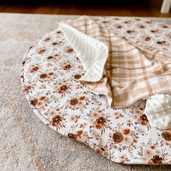 Cotton Playmat with a Brown and moroon floral pattern set out on a floor rug