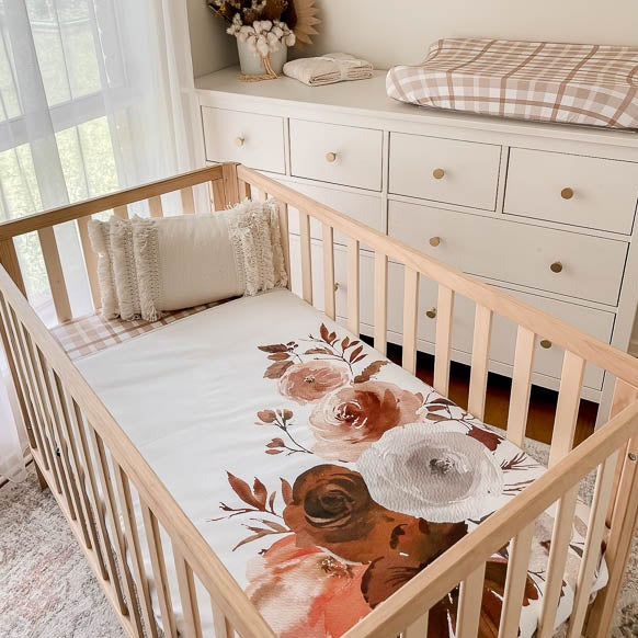 Styled nursery with plaid sheets and change pad cover showcasing the willow large print crib quilt.